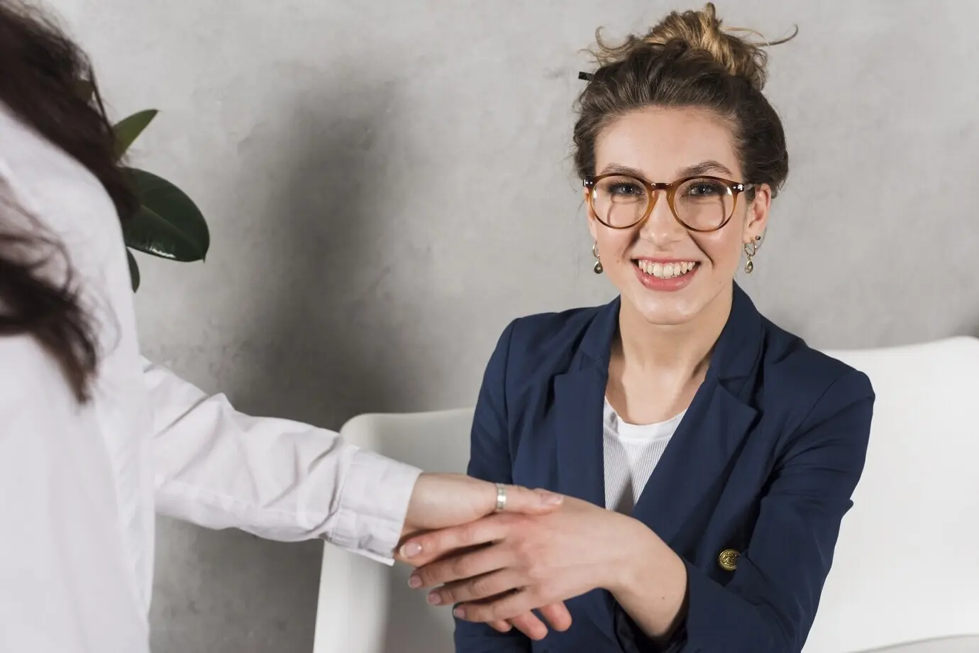 Vista frontal de la mano de una mujer estrechando la mano de una persona de recursos humanos.